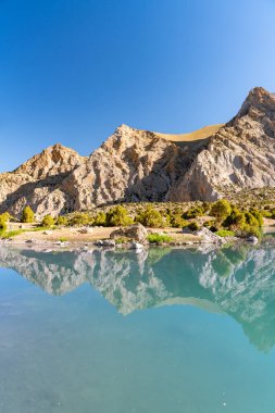 Pamir sıradağları manzarası ve Tacikistan 'daki Fann Dağları' ndaki Kulikalon Gölü 'ndeki huzurlu kamp alanı. Saf buz gölünün rengarenk yansıması.