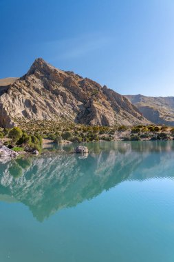 Pamir sıradağları manzarası ve Tacikistan 'daki Fann Dağları' ndaki Kulikalon Gölü 'ndeki huzurlu kamp alanı. Saf buz gölünün rengarenk yansıması.