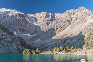 Pamir sıradağları manzarası ve Tacikistan 'daki Fann Dağları' ndaki Kulikalon Gölü 'ndeki huzurlu kamp alanı. Saf buz gölünün rengarenk yansıması.