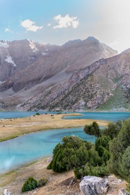 Pamir sıradağları manzarası ve Tacikistan 'daki Fann Dağları' ndaki Kulikalon Gölü 'ndeki huzurlu kamp alanı. Saf buz gölünün rengarenk yansıması.
