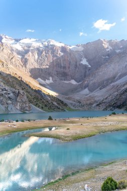 Pamir sıradağları manzarası ve Tacikistan 'daki Fann Dağları' ndaki Kulikalon Gölü 'ndeki huzurlu kamp alanı. Saf buz gölünün rengarenk yansıması.