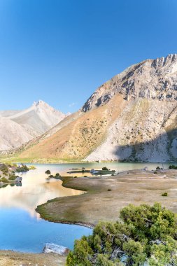 Pamir sıradağları manzarası ve Tacikistan 'daki Fann Dağları' ndaki Kulikalon Gölü 'ndeki huzurlu kamp alanı. Saf buz gölünün rengarenk yansıması.