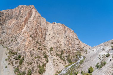 Güzel dağ yürüyüşü yolu açık mavi gökyüzü ve Tacikistan 'daki Fann dağlarında kayalık tepeler.