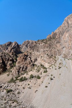 Güzel dağ yürüyüşü yolu açık mavi gökyüzü ve Tacikistan 'daki Fann dağlarında kayalık tepeler.