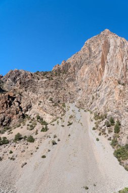 Güzel dağ yürüyüşü yolu açık mavi gökyüzü ve Tacikistan 'daki Fann dağlarında kayalık tepeler.