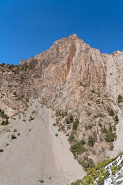 Güzel dağ yürüyüşü yolu açık mavi gökyüzü ve Tacikistan 'daki Fann dağlarında kayalık tepeler.