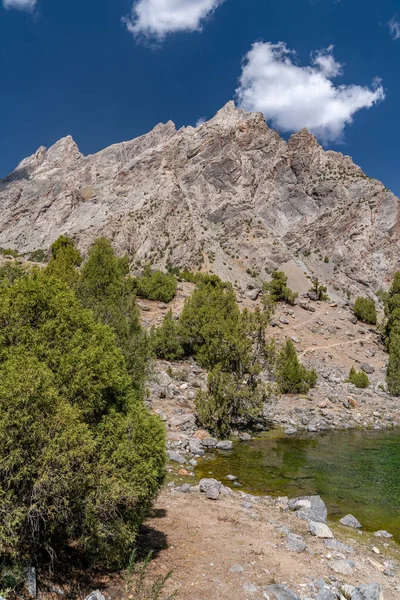 Temiz mavi gökyüzü, kayalık tepeler ve Tacikistan 'daki Fann Dağları' ndaki Alaudin Gölü manzaralı güzel dağ yürüyüşü yolu.