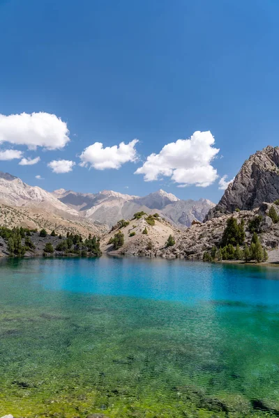 Temiz mavi gökyüzü, kayalık tepeler ve Tacikistan 'daki Fann Dağları' ndaki Alaudin Gölü manzaralı güzel dağ yürüyüşü yolu.