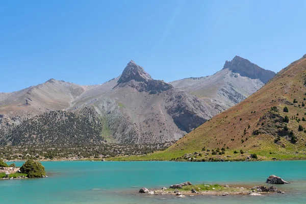 Pamir sıradağları manzarası ve Tacikistan 'daki Fann Dağları' ndaki Kulikalon Gölü 'ndeki huzurlu kamp alanı. Saf buz gölünün rengarenk yansıması.