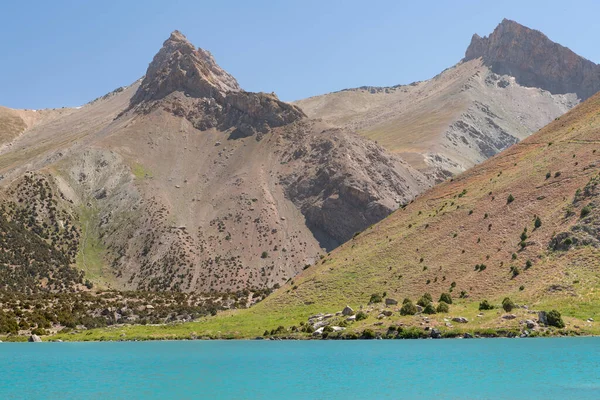 Pamir sıradağları manzarası ve Tacikistan 'daki Fann Dağları' ndaki Kulikalon Gölü 'ndeki huzurlu kamp alanı. Saf buz gölünün rengarenk yansıması.