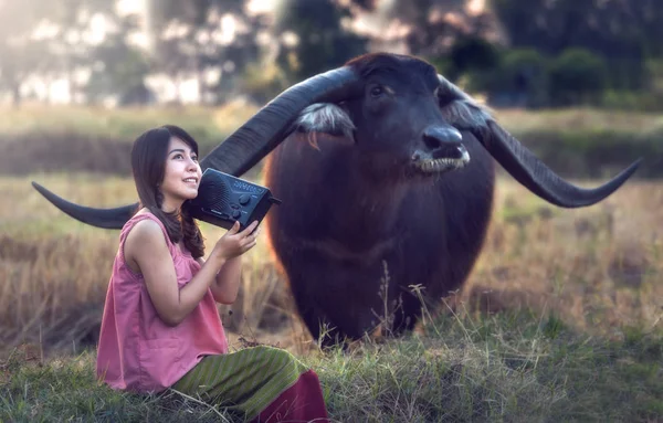 Asiatisk kvinna lyssna radio med hennes buffel, Thailand — Stockfoto