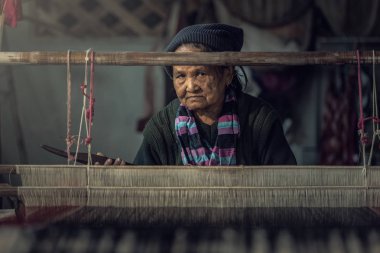 Yaşlı kadınlar Tayland ipeği dokuma prosedürünü gösteriyor.
