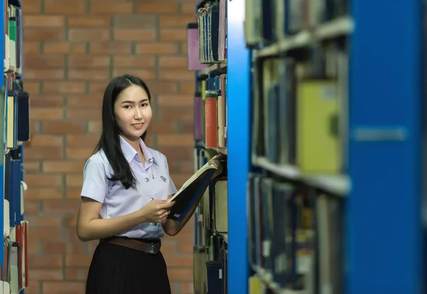 Žena studenti jsou několik knih polici v knihovně — Stock fotografie