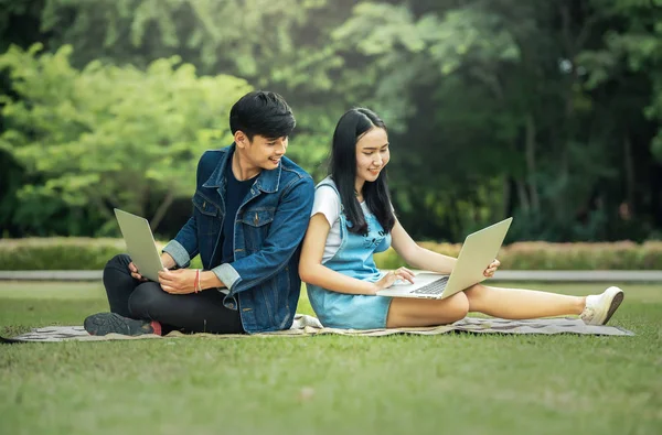 Young student using laptop together in the park — Stock Photo, Image