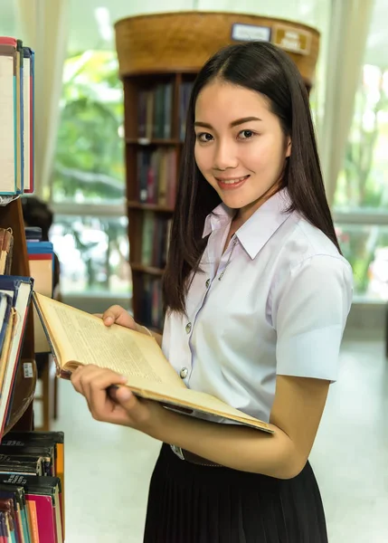 Kvinna studenter finns en handfull böcker i bokhyllan i biblioteket — Stockfoto
