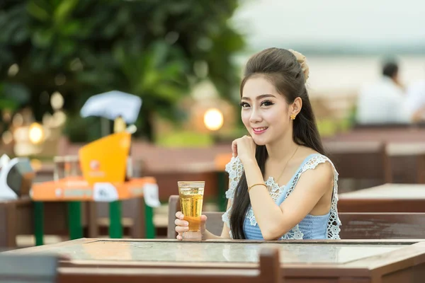 Mujer bebiendo cerveza en la cafetería. Hermosa joven asiática — Foto de Stock