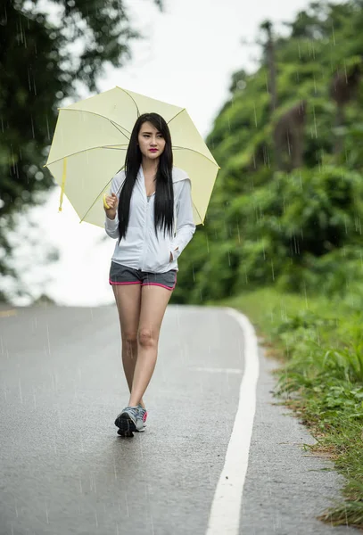 Mujer con paraguas amarillo solo mientras llueve —  Fotos de Stock