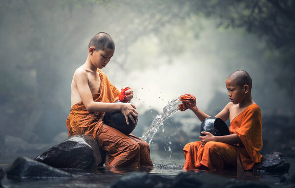 Asian Novice monks cleaning alms bowl in creeks