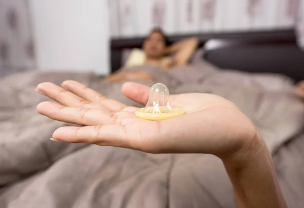 Жінка показує презерватив на ліжку — стокове фото