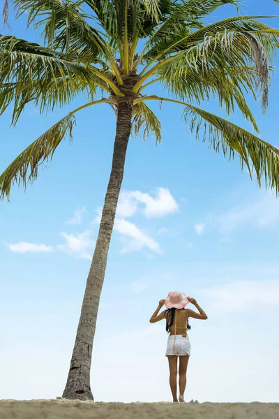 Vrouw aan het strand met een palmboom — Stockfoto