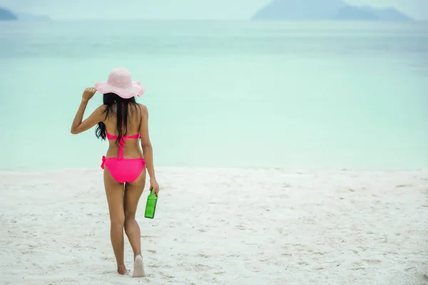 Mujer joven caminando con botella de cerveza en la playa — Foto de Stock