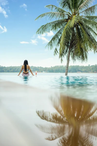 Woman relaxing in infinity swimming pool — Stock Photo, Image