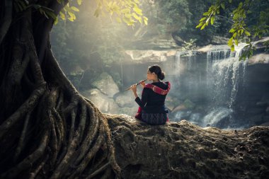 Girl plays the wood flute in nature background clipart