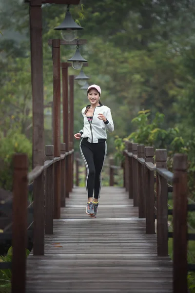 Jeune femme coureuse courir sur un pont en bois — Photo