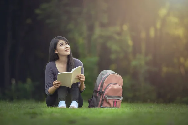 幸せな魅力的なアジアの女性の肖像屋外で本を読む — ストック写真