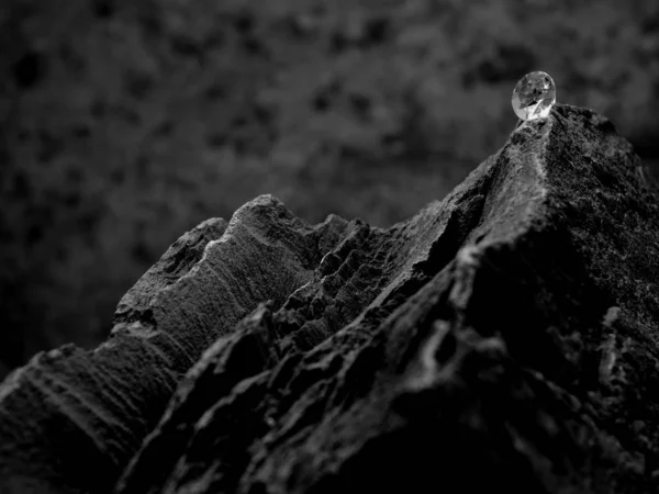 黒と白の石の背景を持つ宝石のファセットカットを示す岩の上に 強いコントラストの単一のダイヤモンド — ストック写真