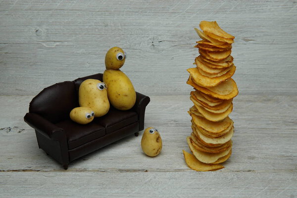 A Couch Potato, Showing a New Vegetable Family on a Sofa Chair with a Fried Stack of Chips on a Wooden Plank Display Board.