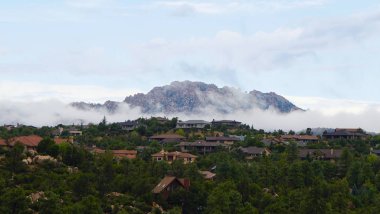 Granite Mountain clothed in low misty clouds as morning comes to Northern Arizona. clipart