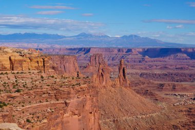 Arkasında karla kaplı dağlarla Canyonlands Ulusal Parkı 'nın geniş kırmızı kaya kanyonlarına bakıyorum..