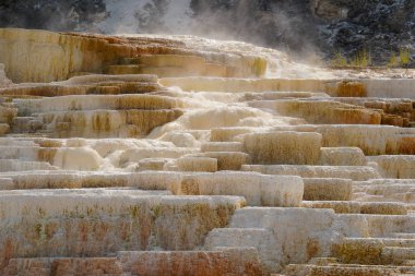 Sonbahar güneşi, çok katmanlı teraslarda çağlarken buharlı mineral dolu şelaleden parlıyor..