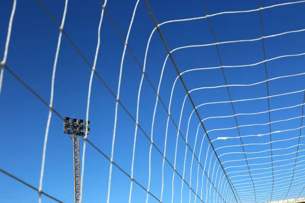 The football field lights have a net in front.