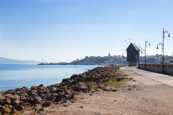 Strada in riva al mare con mulino a vento Foto Stock