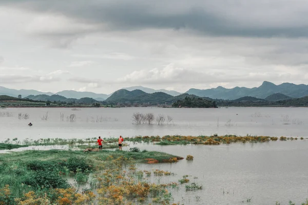 Çimlerin üzerinde yürüyen iki çocukla dolu bir baraj..