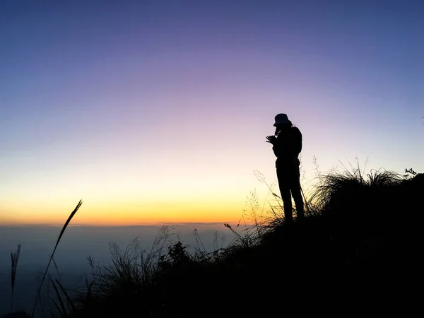 一个女人站在山上 在黄昏的阳光下 坐着的照片 — 图库照片