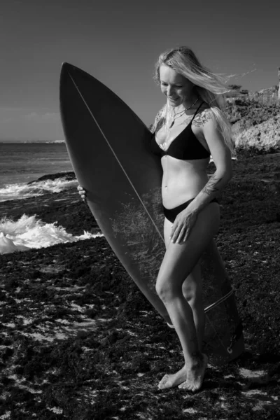Monocromo. Chica surfista con tabla de surf en la playa. Mujer sexy joven con bikini negro. Chica surfista preparándose para surfear. Bali, Indonesia —  Fotos de Stock