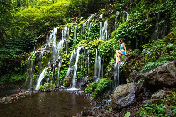 Jeune femme caucasienne assise sur le rocher et enjoiyng paysage de cascade. Mode de vie. Cascade de Banyu Wana Amertha Wanagiri, Bali . — Photo