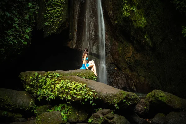 Jeune femme caucasienne assise sur le rocher et enjoiyng paysage de cascade. Concept de voyage. Leke Leke cascade, Bali . — Photo