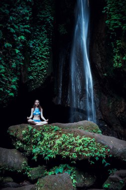 Genç beyaz kadın meditasyon yapıyor, şelalede yoga yapıyor. Gyan Mudra. Leke Leke Şelalesi, Bali, Endonezya. 