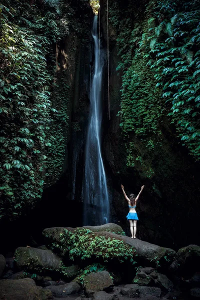 Femme caucasienne excitée levant les bras devant la cascade. Vue de dos. Leke Leke cascade, Bali, Indonésie . — Photo