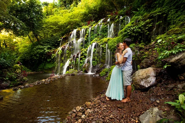 Happy multiracial couple hugging. Mixed couple in love near waterfall in tropical forest. Love story. Wana Amertha waterfall Wanagiri, Bali