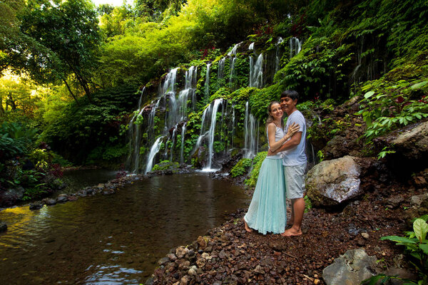 Happy multiracial couple hugging. Mixed couple in love near waterfall in tropical forest. Romantic relation. Wana Amertha waterfall Wanagiri, Bali