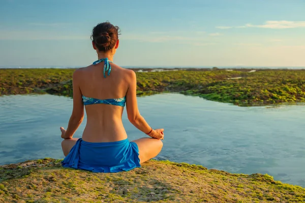 Giovane donna, meditare, praticare yoga e pranayama in spiaggia. Pratica di yoga al tramonto. Mani nel mudra gyan. Vista da dietro. Spiaggia di Melasti, Bali — Foto Stock