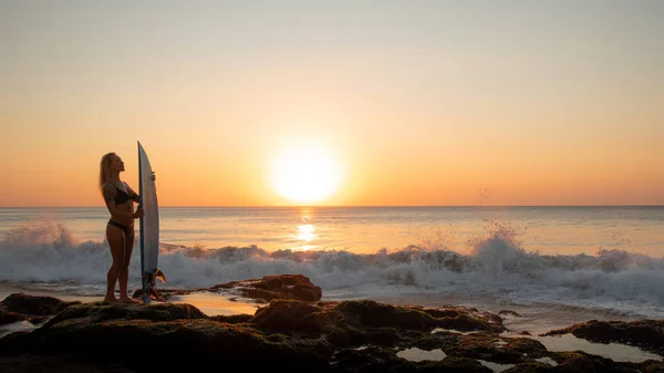 Surf-Lifestyle. Silhouette eines Surfermädchens mit Surfbrett am Strand. goldener Sonnenuntergang. bali, indonesien — Stockfoto