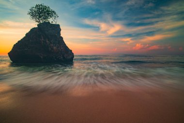 İnanılmaz bir deniz manzarası. Gün batımında plaj. Okyanusta ağaçlı taş. Kapama hızı yavaş. Bingin Sahili, Bali