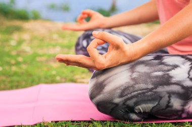 Lotus pozu. Gyan Mudra 'yı kapatın. Bir ele odaklan. Yoga dışarıda. Yoga minderinde oturan genç bir kadın, meditasyon yapıyor, Gyan Mudra ile pranayama yapıyor. Yoga yaşam tarzı. Endonezya 'daki Bali tropikal adası