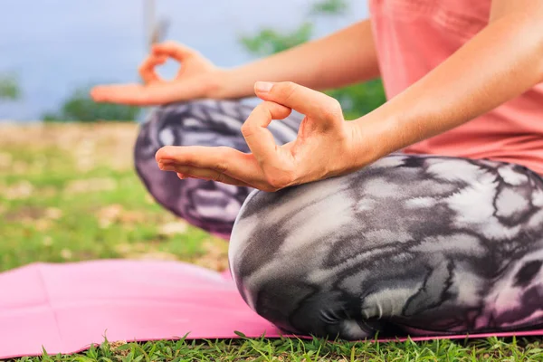 Lotus pose. Close up gyan mudra. Focus on one hand. Yoga outdoor. Young woman sitting on yoga mat, meditating, practicing pranayama with gyan mudra. Yoga lifestyle. Bali tropical island, Indonesia